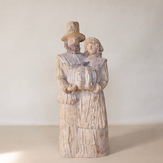 Wooden figurine of a couple holding a heart against a white background