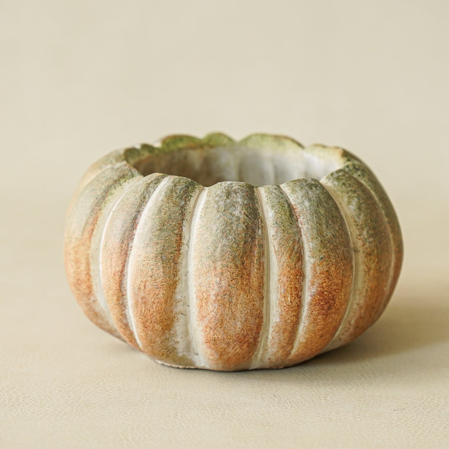 Decorative pumpkin with ribbed texture on a beige background