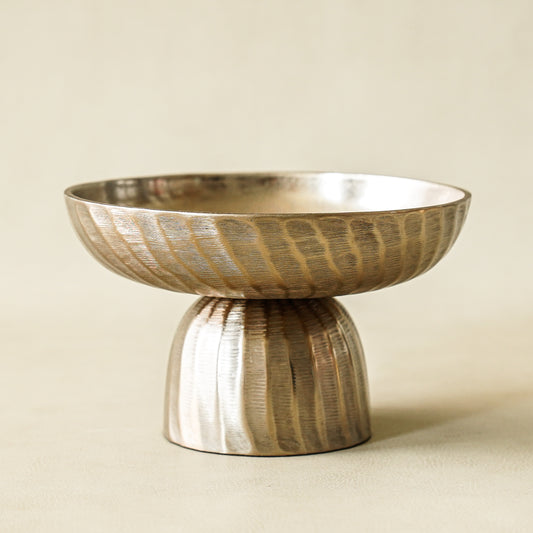 Decorative metallic bowl with textured design on a beige background