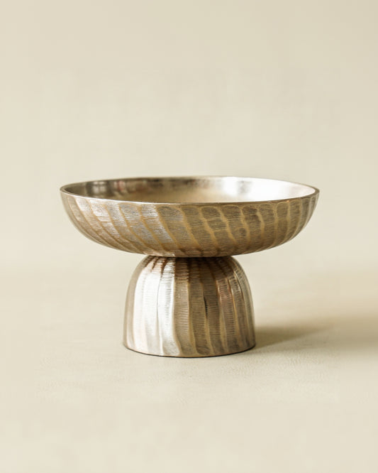 Decorative metallic bowl with textured design on a beige background