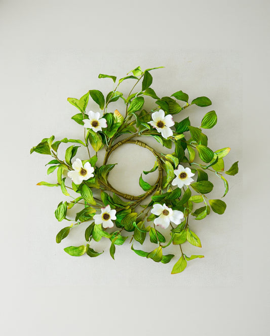 Decorative wreath with green leaves and white flowers on a light gray background