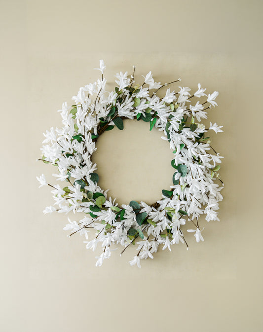 Floral wreath with white flowers and green leaves on a beige background