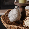 Decorative bird figurine on a woven basket with a blurred background