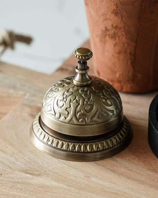 Decorative brass bell on a wooden surface with a blurred background