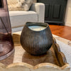 Decorative candle in a textured holder on a wooden surface with a blurred background