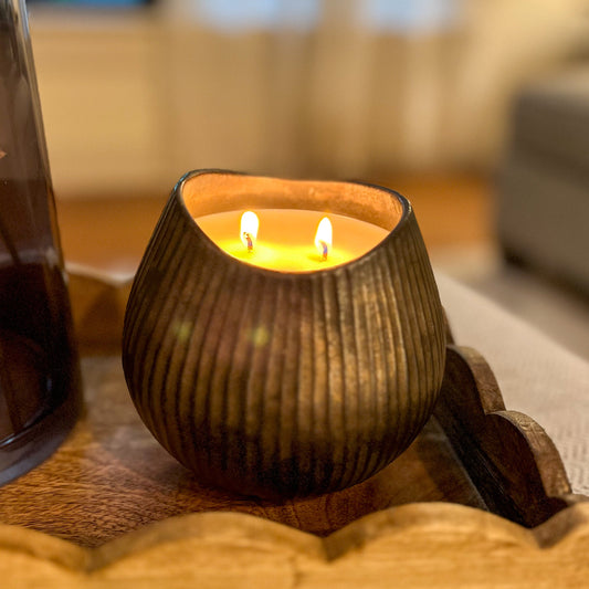 Ceramic candle holder with two lit candles on a wooden surface.