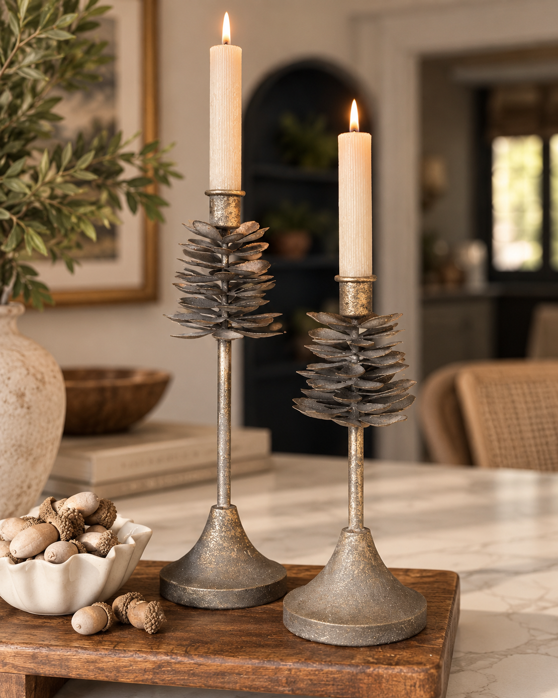 Set of two antique gold iron pinecone taper candle holders with layered pinecone detailing and graduated heights