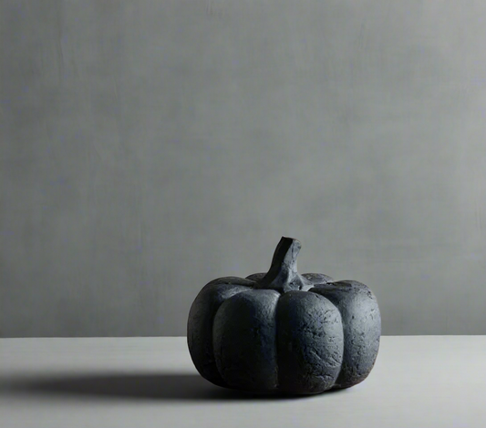 Decorative black pumpkin on a wooden surface with a neutral background