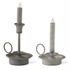Two metallic candle holders with lit candles on a white background