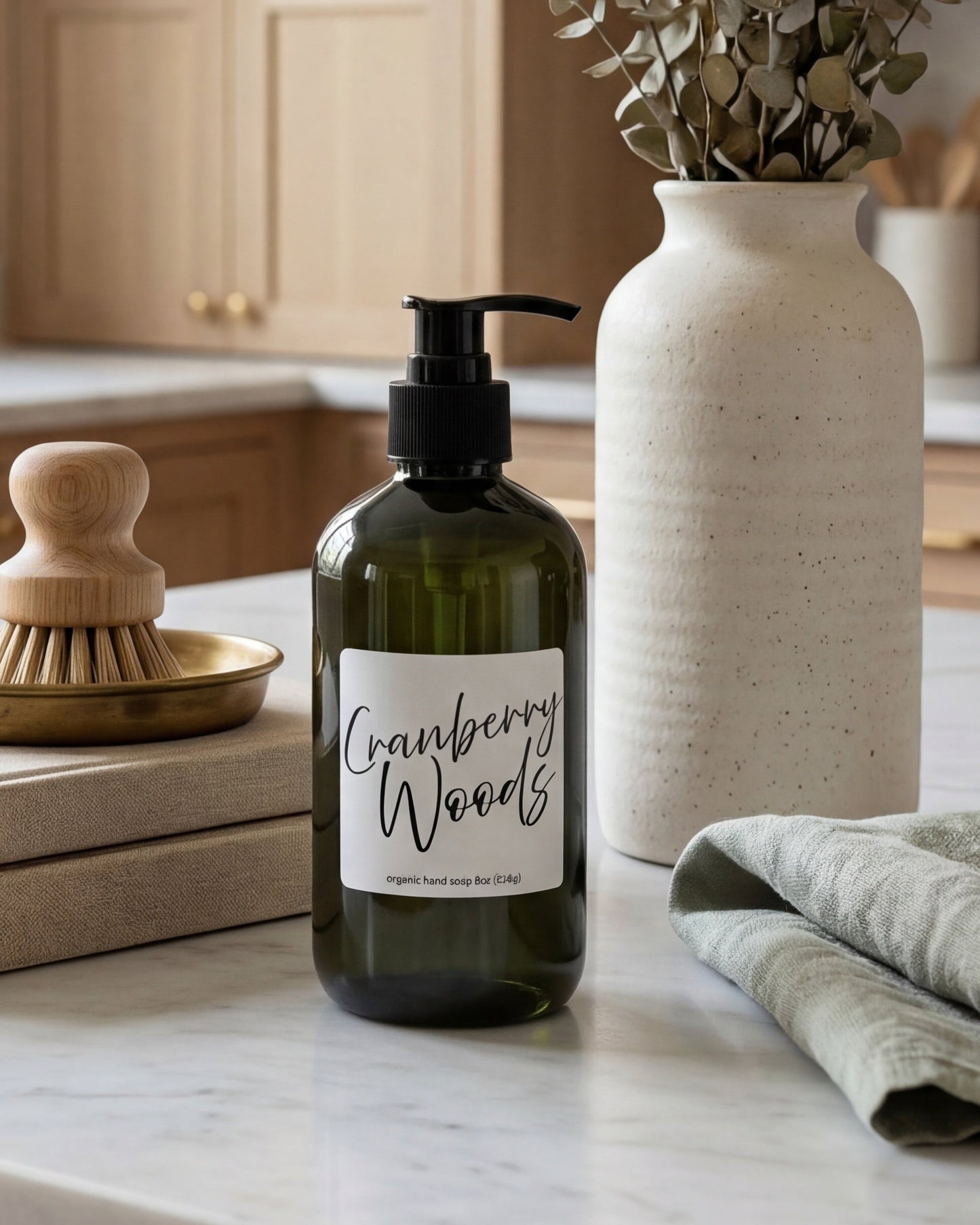 Kitchen counter with a bottle labeled 'Cranberry Woods', a vase with greenery, and books.