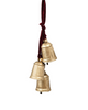 Decorative brass bells hanging against a white fireplace with candles and greenery.