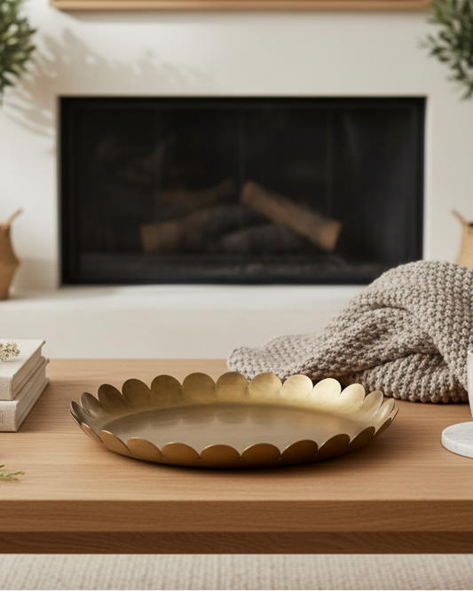 Living room with a wooden coffee table, gold tray, and decorative items in front of a fireplace.