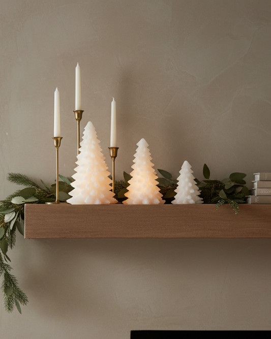 Decorative mantel with candles and Christmas trees in a living room setting.