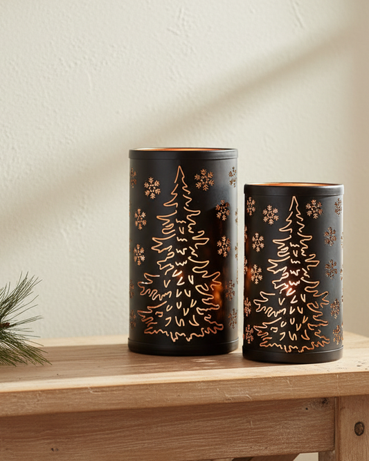 Two black candle holders with tree and snowflake patterns on a wooden table.