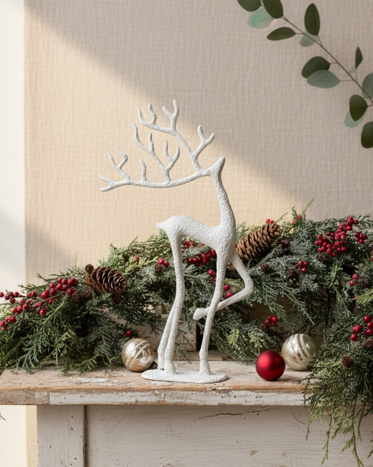 Decorative reindeer figure on a mantel with Christmas garland and ornaments.