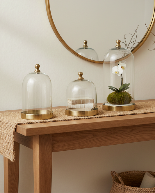 Decorative table with glass cloches, a plant, and a vase against a neutral wall.