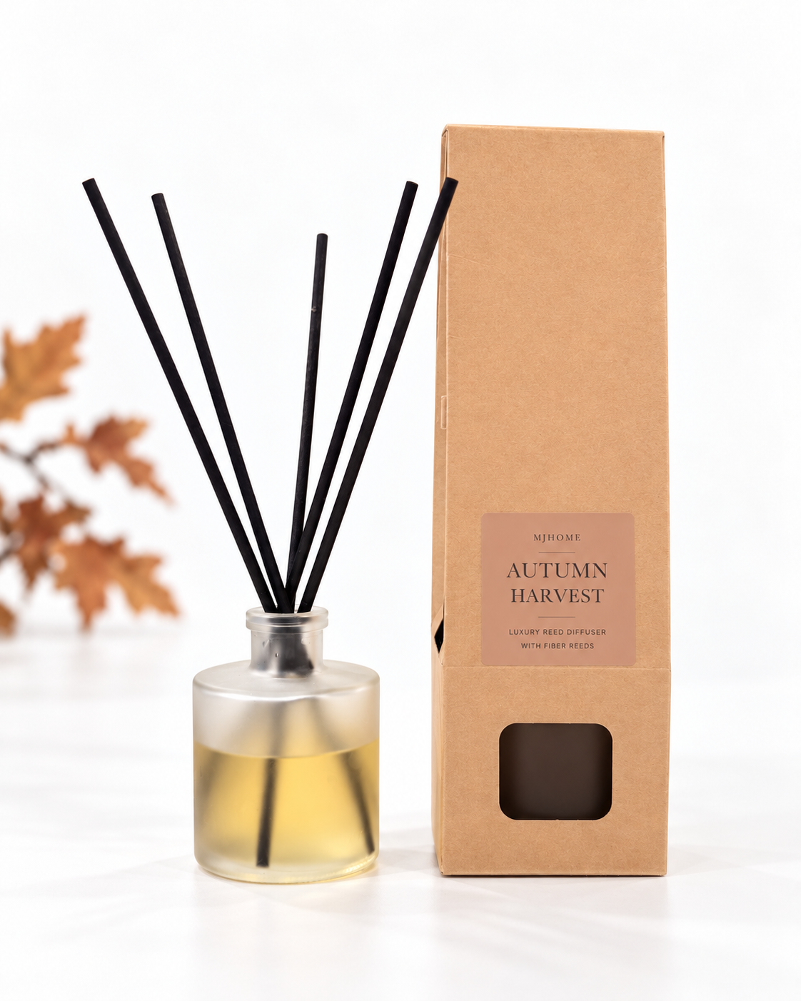 MJHome Autumn Harvest reed diffuser with frosted bottle, five reeds and kraft box on a clean white background with subtle autumn leaves