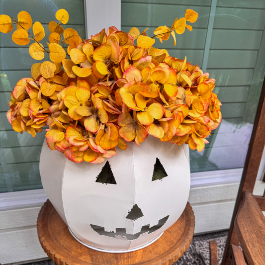 Decorative pumpkin vase with floral arrangement on a wooden stool