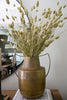 Bronze vase with dried plants on a table