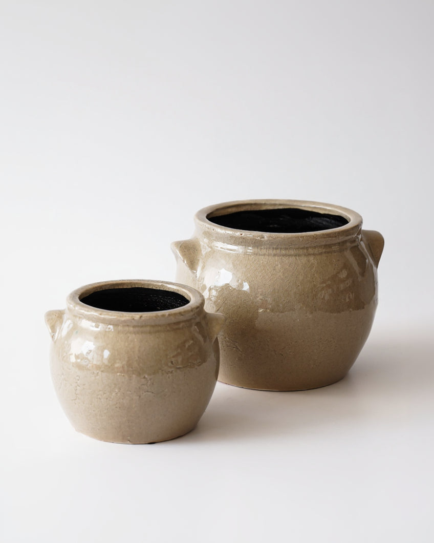 Two beige ceramic pots with black interior on a white background