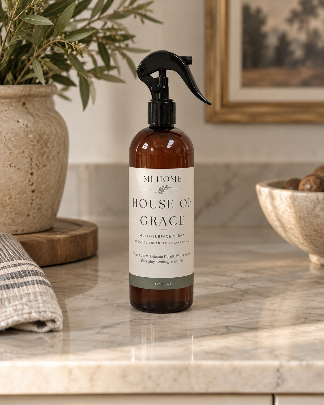 MJHome House of Grace multi-surface cleaning spray in an amber bottle with black trigger sprayer, part of the Signature Home Fragrance Collection