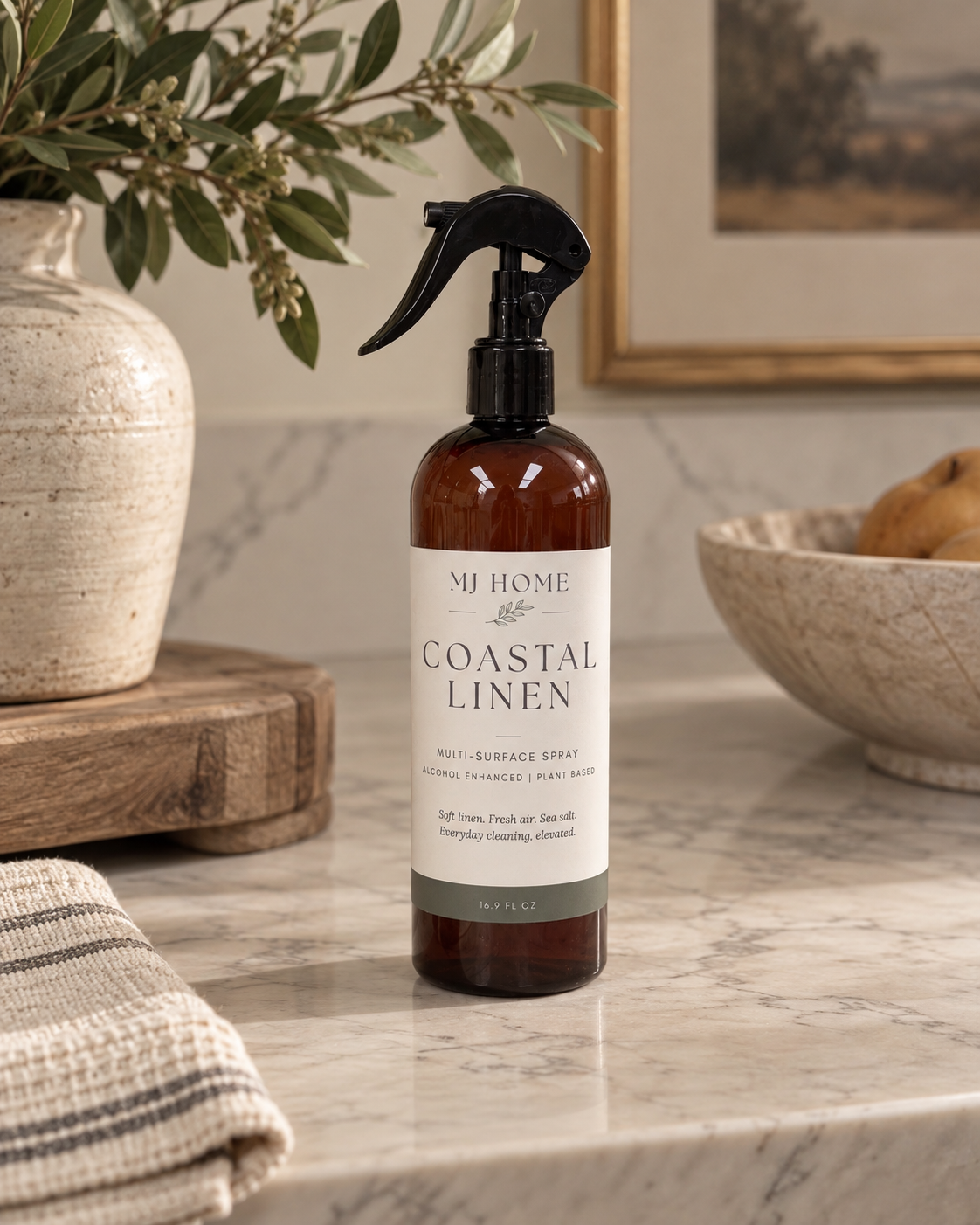 MJHome Coastal Linen multi-surface cleaning spray in an amber bottle with black trigger sprayer, part of the Signature Home Fragrance Collection
