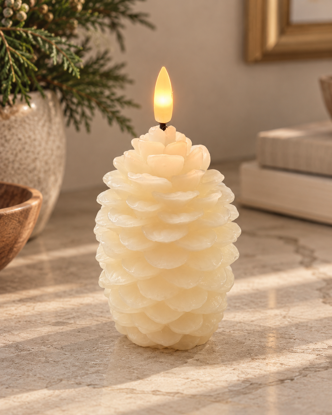 Ivory flameless LED pinecone candle with layered pinecone detailing and warm glowing flame