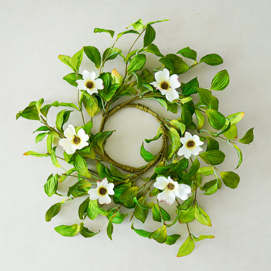 Decorative wreath with green leaves and white flowers on a light gray background