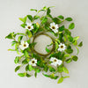 Decorative wreath with green leaves and white flowers on a light gray background