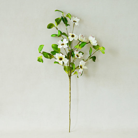 Artificial flower branch with white flowers and green leaves on a light gray background