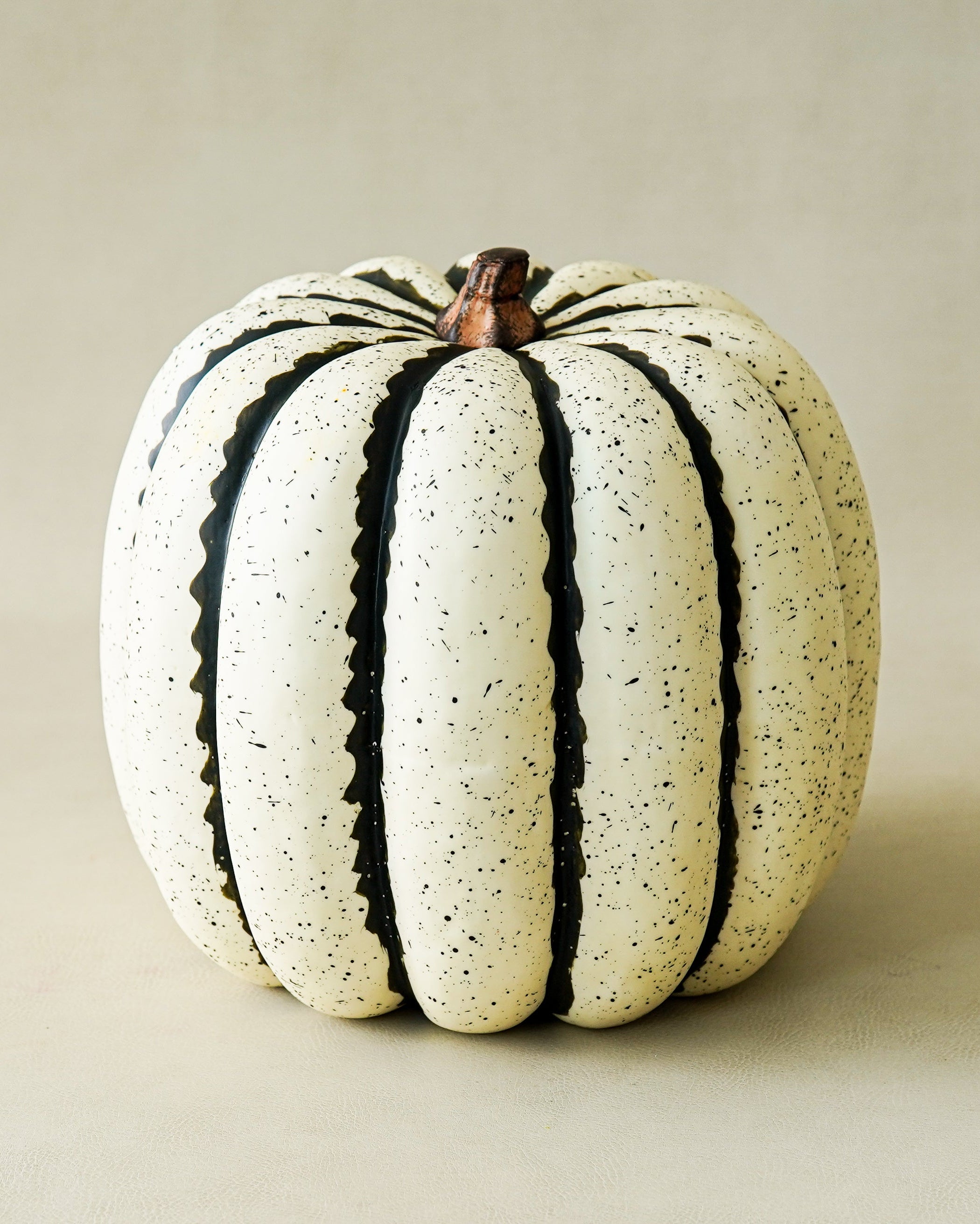 White pumpkin with black stripes on a beige background