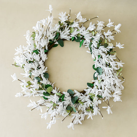 Floral wreath with white flowers and green leaves on a beige background