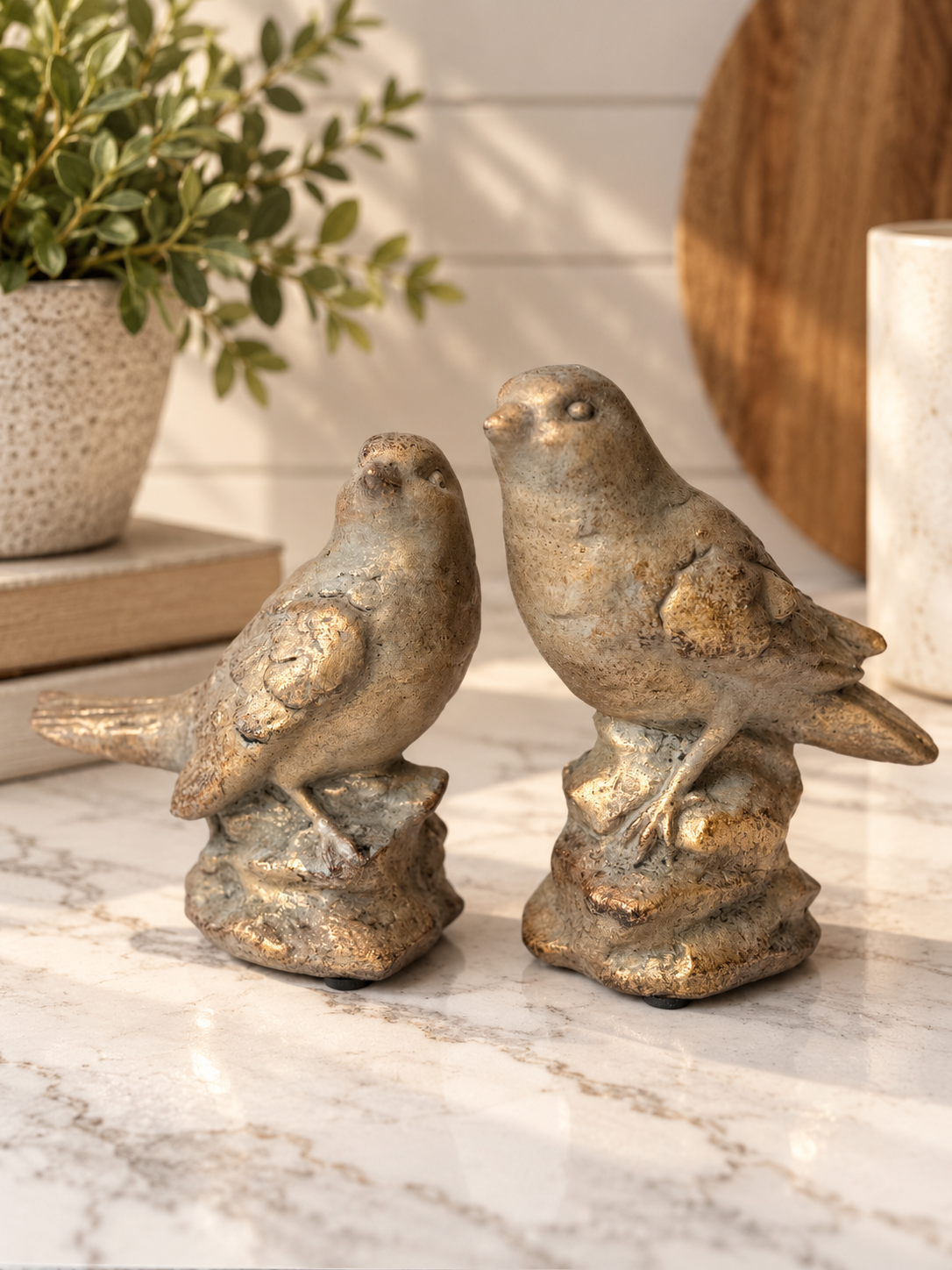 Set of two weathered cement bird figurines with textured gray and antique gold finishes, sculpted feather details and decorative bases