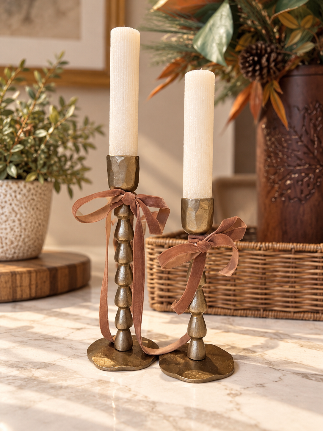 Set of two antique gold iron taper candle holders with decorative stacked-bead stems, ivory taper candles and velvet ribbon bows