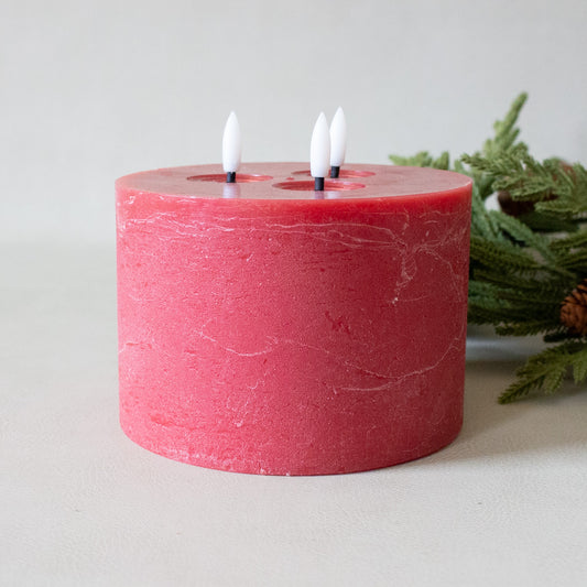 Red candle with three small candles inside on a light background