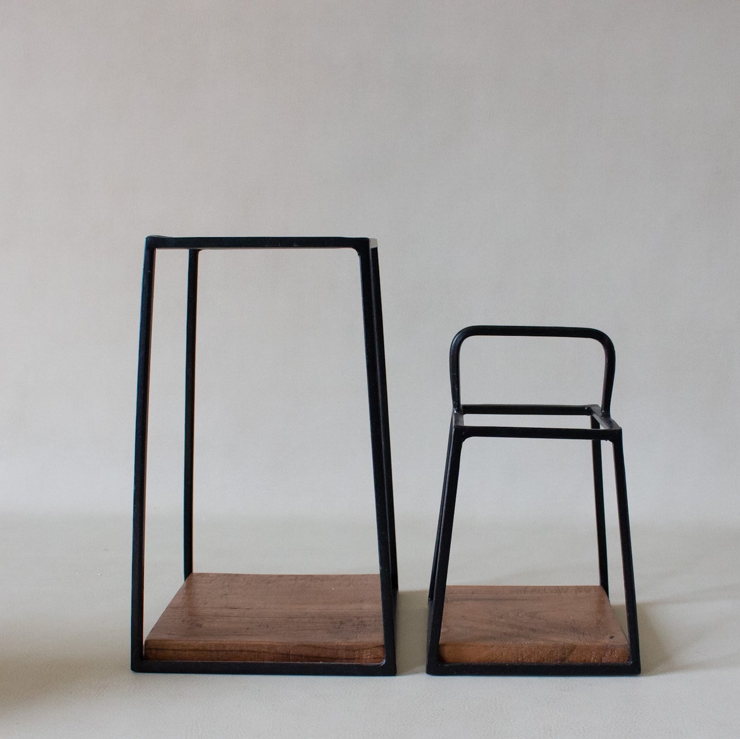 Two wooden stools with black metal frames on a white background