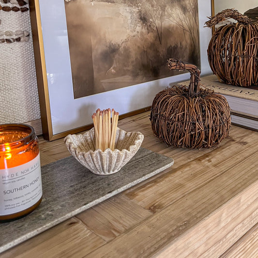 Decorative setup on a wooden surface with pumpkins, a candle, and a lamp.