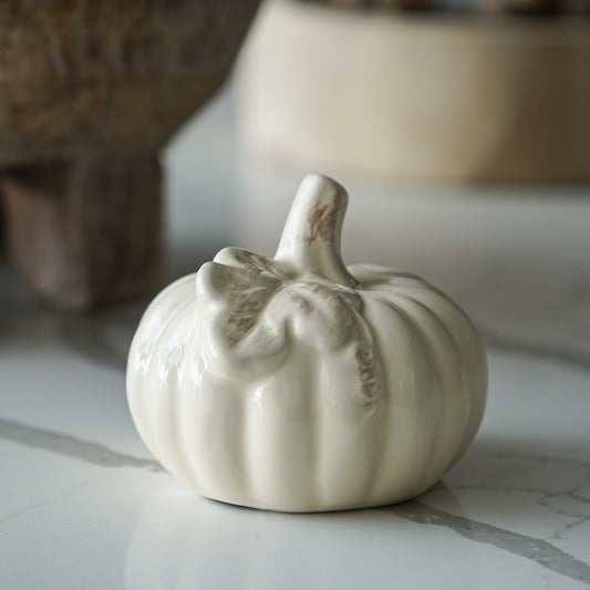 White ceramic pumpkin on a marble surface with a blurred background