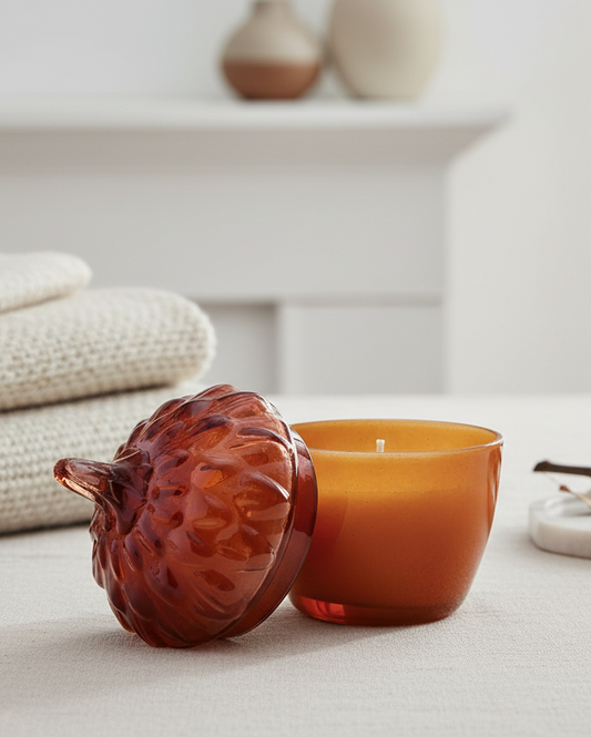 Candle with decorative container on a light surface, with neutral background