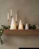 Decorative mantel with candles and Christmas trees in a living room setting.
