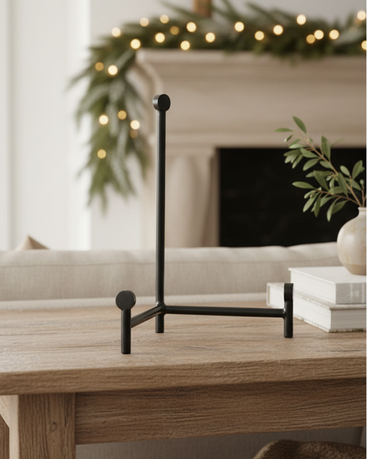 Decorative stand on a wooden table with a fireplace and garland in the background