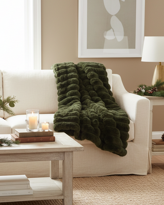 Living room with a beige sofa, green blanket, and decorative items.