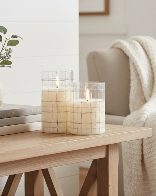 Candle on a wooden table with books and a vase in a cozy living room setting.