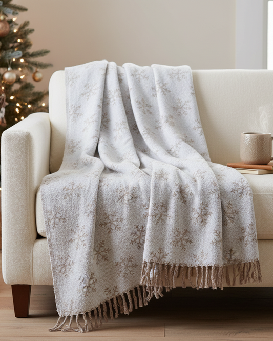 White floral-patterned throw blanket draped over a beige sofa in a cozy living room with a Christmas tree.