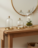 Decorative table with glass cloches, a plant, and a vase against a neutral wall.