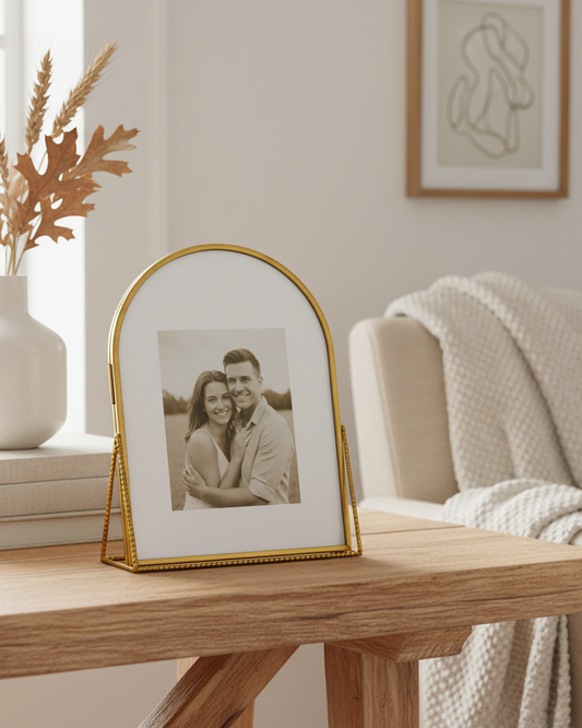 Gold-framed photo of a couple on a wooden table with decorative elements.
